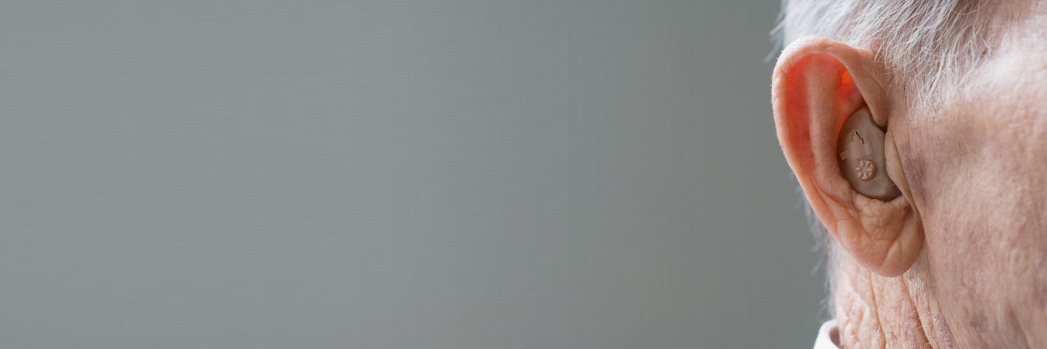 A close up of a hearing aid in an elderly person's ear